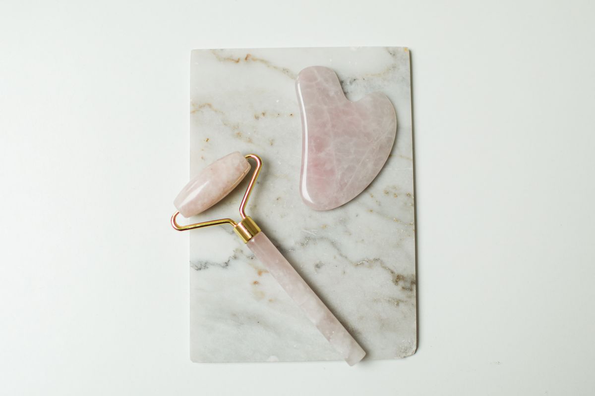 Jade roller and gua sha tools on marble surface